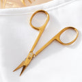 Gold scissors on a white background