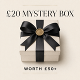 A cream-colored gift box tied with a wide black ribbon and a round gold seal, centered on a light beige background with the text '£20 MYSTERY BOX' above and 'WORTH £50+' below.
