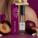 Shay & Blue perfume bottle with packaging and plums on a purple background