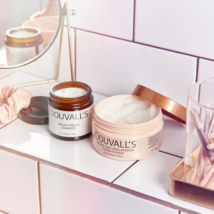 Douvall's hair care products on a bathroom counter with a mirror in the background.