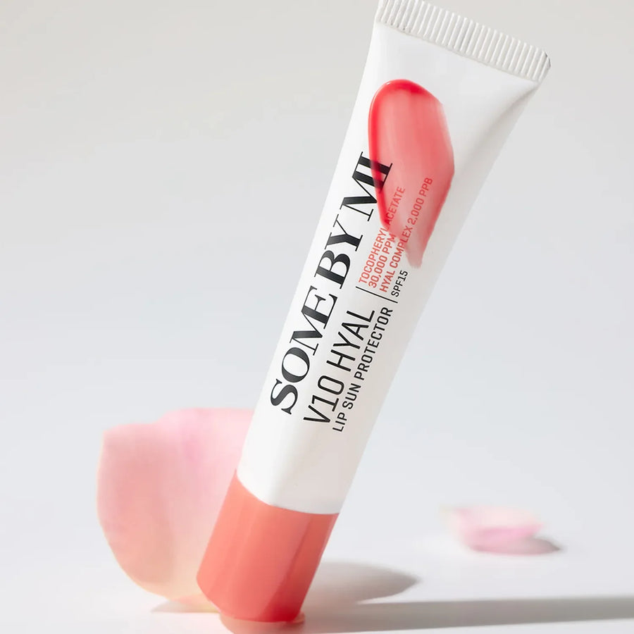 Lip balm tube with coral cap and white body on a light gray background