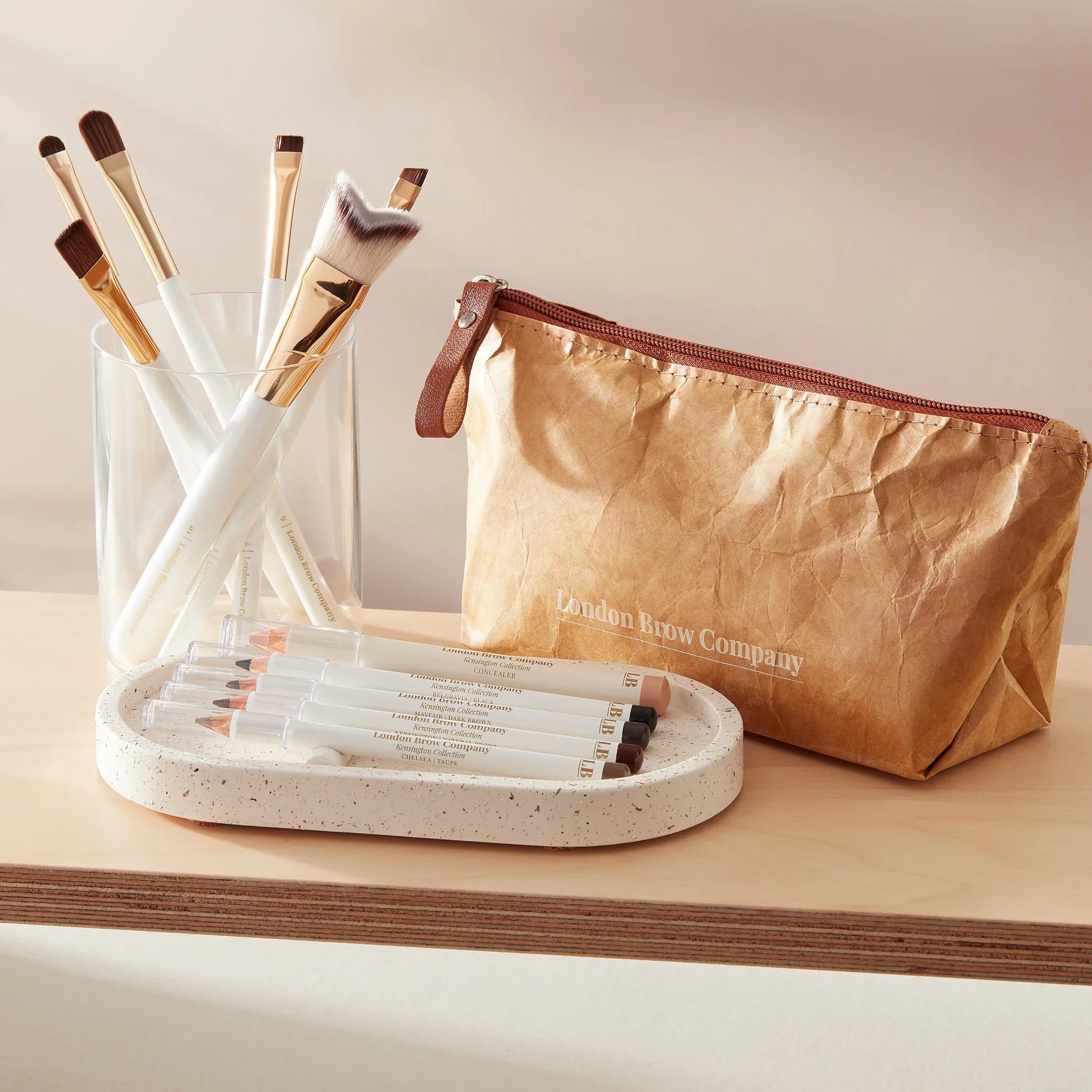 Makeup brush with white handle and gold ferrule on a green background