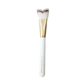 Makeup brush with white handle and gold ferrule on a green background