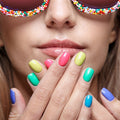 Close-up of a person with colorful nail polish wearing sunglasses with a candy-like frame.