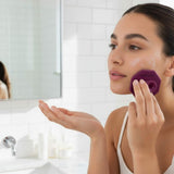 ScrubMeFace Passionate Purple facial cleansing brush by bathroom sink